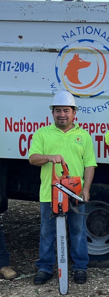 Crew member with a saw beside the truck